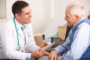 Old man talks with his doctor over medical paperwork.