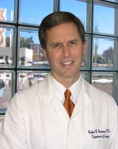 Robert Cameron in white coat in front of window