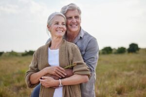 Mature man and woman holding one another in front of landscape